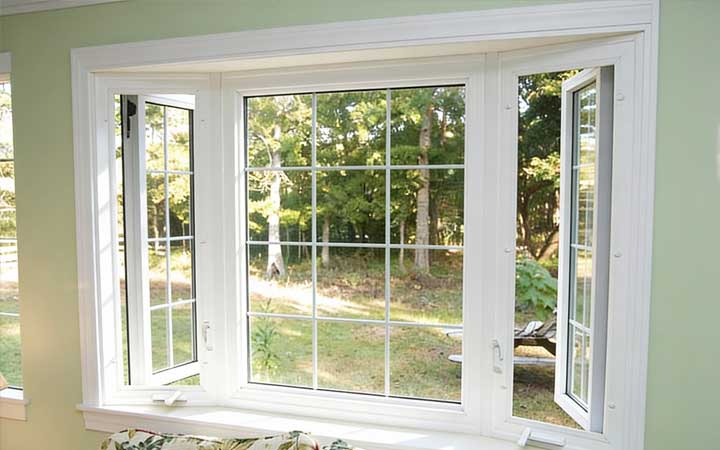 Bright interior bay window with white frames overlooking a residential city street and brick buildings, filling the room with natural light and showcasing professional Window Replacement Atlanta services for enhanced comfort and energy efficiency.