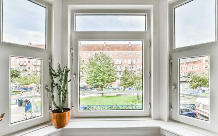 Interior bay window with white frames and decorative accents overlooking brick apartment buildings, enhancing natural light and city views while showcasing professional Window Replacement Atlanta services for modern, energy-efficient homes.
