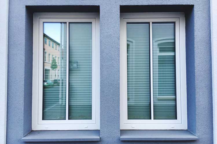 Building exterior with two white-framed sliding windows featuring closed blinds, showcasing clean modern architecture, privacy, and professionally installed Sliding Windows Atlanta for smooth operation and energy efficiency.