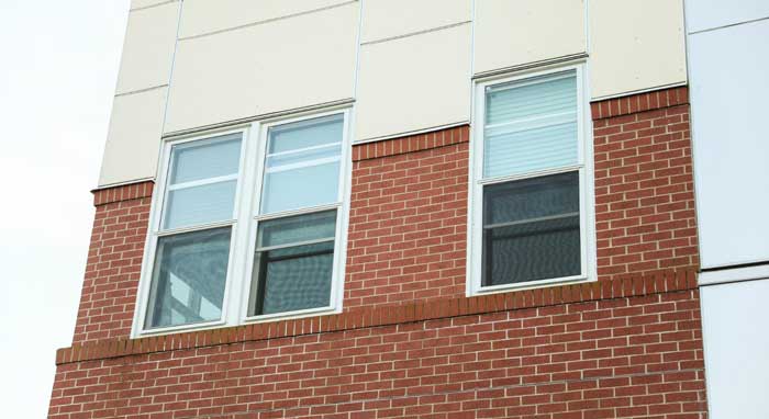 Home exterior featuring a white-framed window with red curtains next to a wooden entry door, showcasing clean siding, updated design, and professional Window Replacement Atlanta services for improved style and energy efficiency.