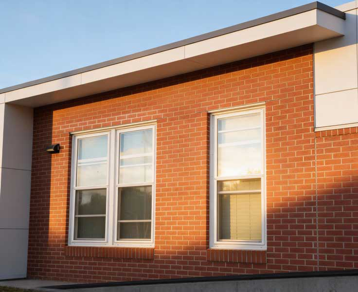 Couple sitting at a table by a large white-framed window enjoying coffee and conversation in a bright modern interior, highlighting natural light, comfort, and professional Window Replacement Atlanta services for stylish, energy-efficient spaces.